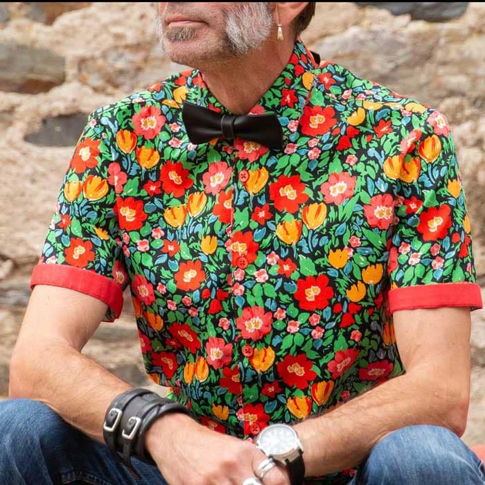 nœud-papillon en cuir sur chemise à fleur, porté par un homme